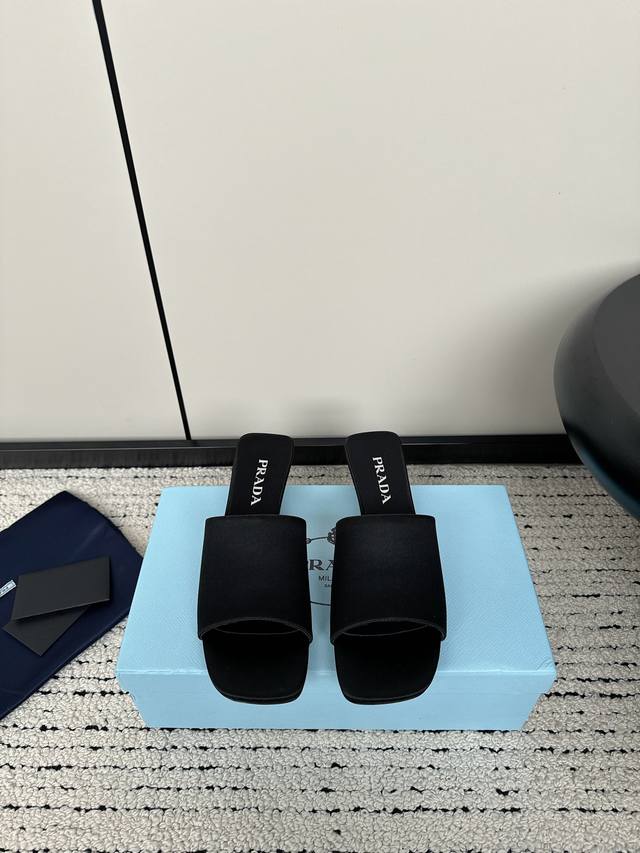 Prada 24Ss夏季新款一字缎面凉拖鞋 这款缎面凉拖鞋以现代主义线条和新颖的建筑感造型为特色，展现出精致优雅的魅力。Prad*三角形标志性的几何形状成为这款