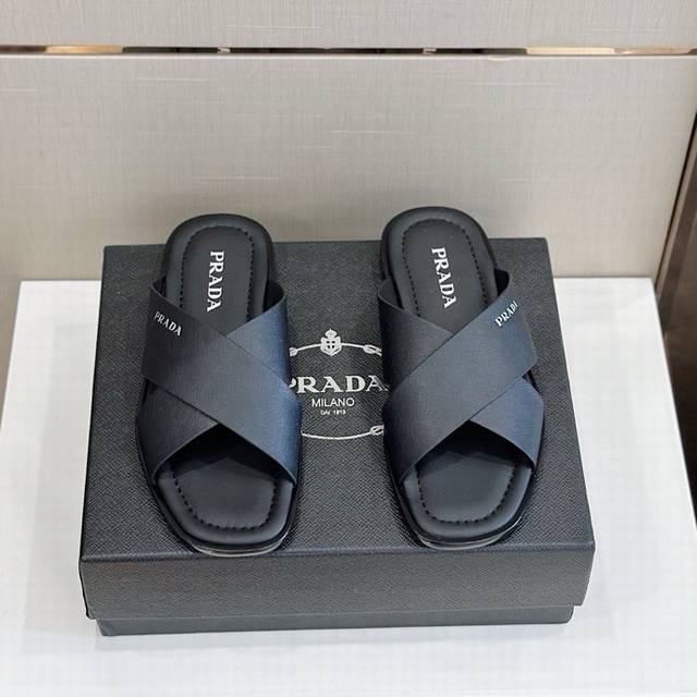 P家最新拖鞋官网同步-真皮大底 这款拖鞋以品牌独特的标志性saffiano牛皮打造，品牌徽标跃于双饰带，品牌格调一览无余。牛皮和真皮大底赋予男性优雅魅力与功能性